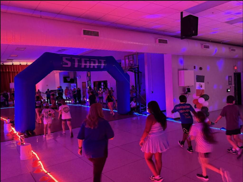 A gymnasium with an arch labeled "START" and purple lights. People are walking and running.