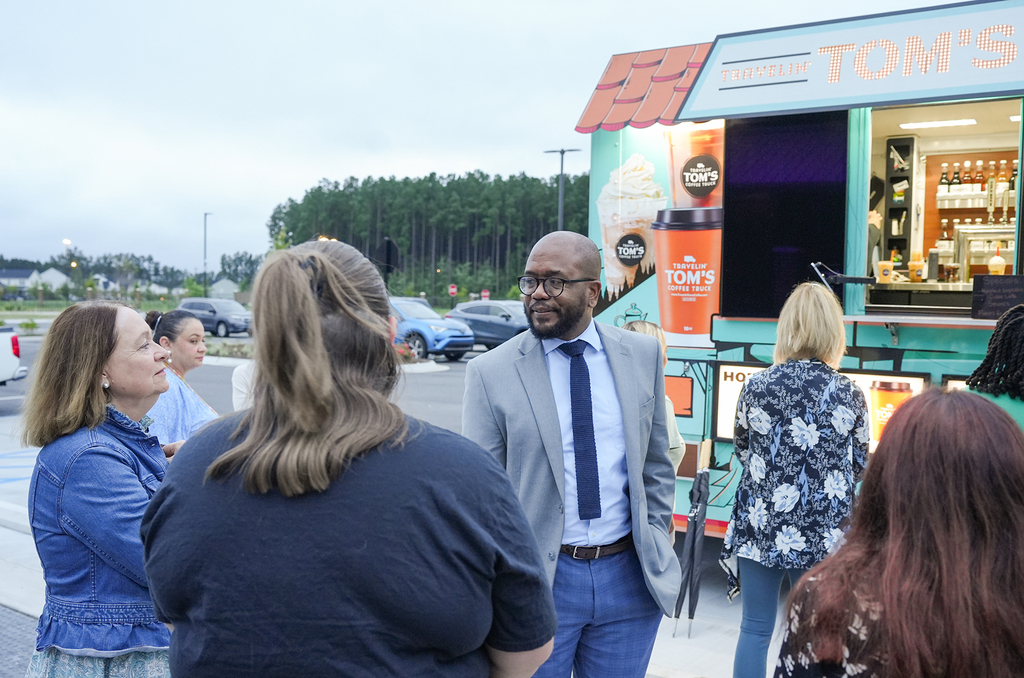 Group of people in front of a food truck. Some are looking at the truck, others are talking.