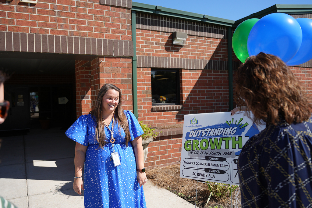 Woman in a blue dress outside a brick building with a banner reading "OUTSTANDING GROWTH".