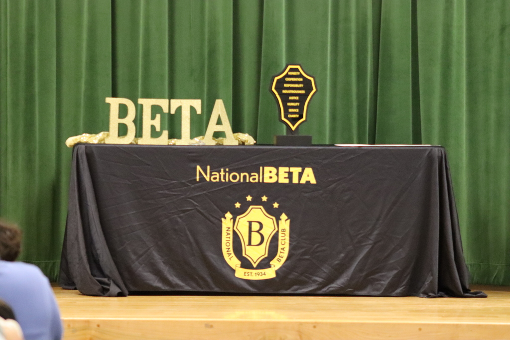 A stage with a black tablecloth and a golden scorpion trophy behind it. "National BETA" logo on the table.