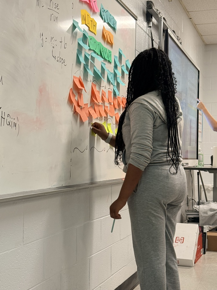 student posting sticky notes with equations