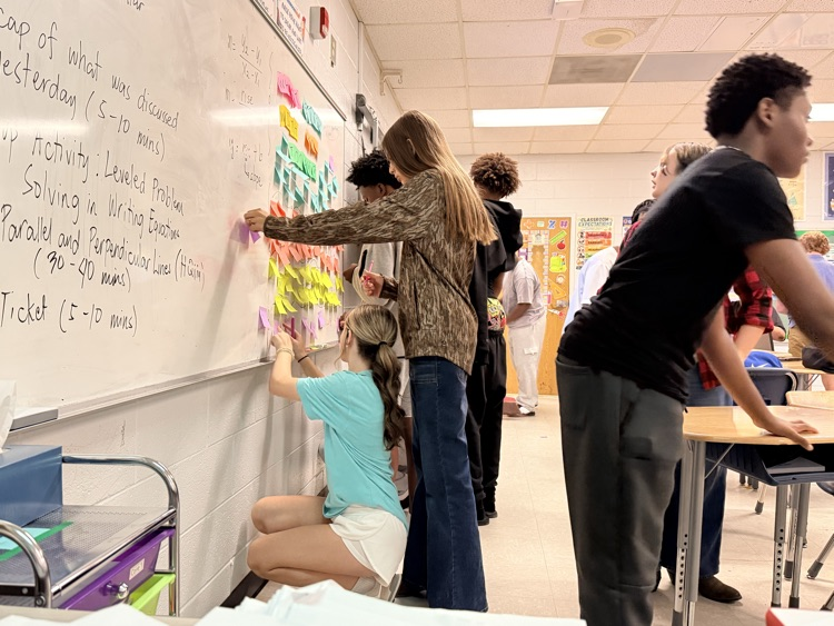 students posting sticky notes with equations