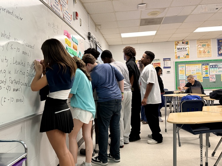 students posting sticky notes with equations