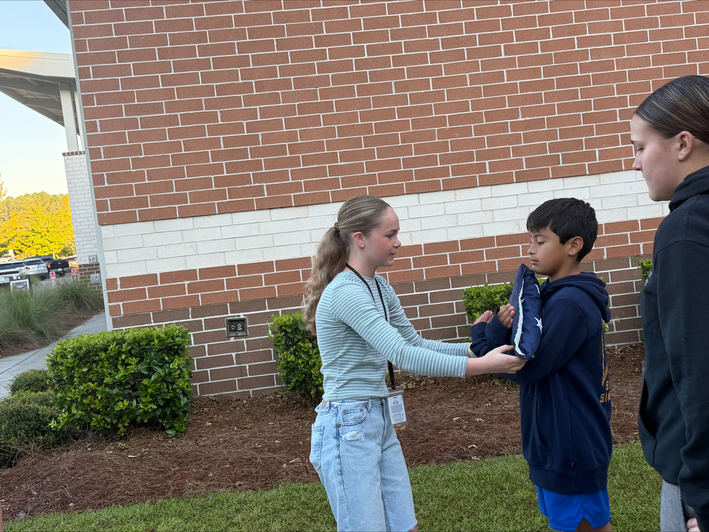 Woman with long hair helping a boy with a blue jacket outside near a brick building.