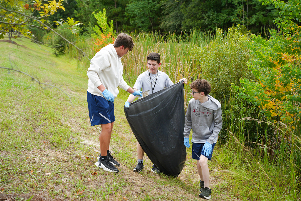 three cadets outside by a pond collecting litter