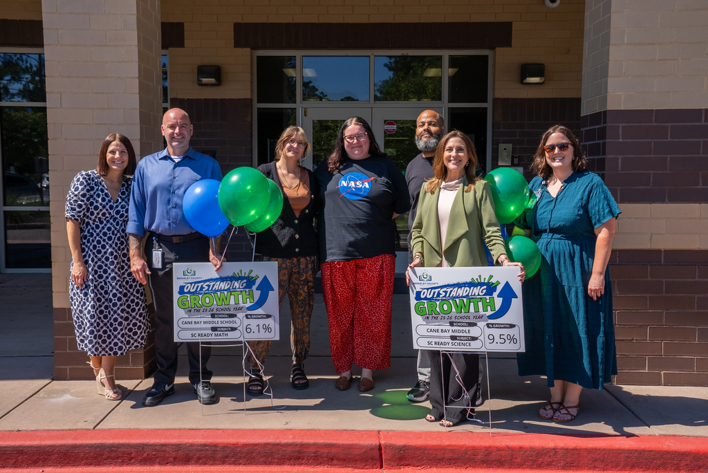 group of CBM staff standing with growth celebration signs