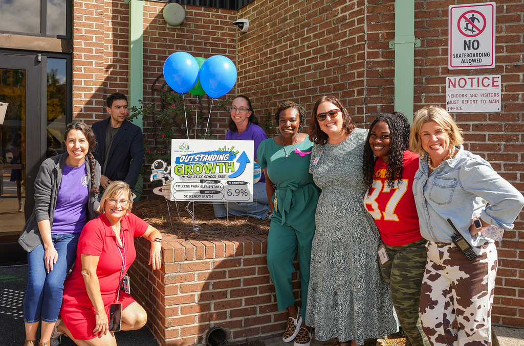 A group of women and men pose for a photo in front of a brick building.