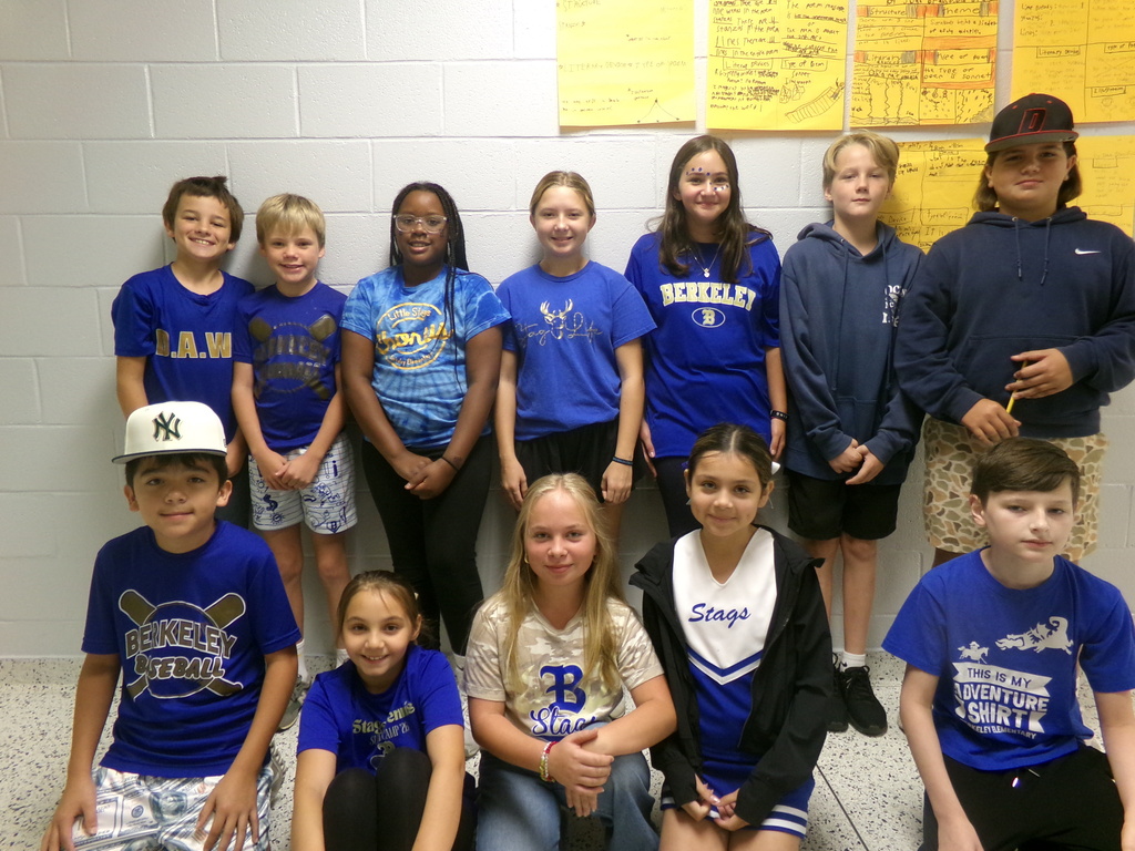A group of children and young people in blue shirts and casual clothing are gathered in a room.