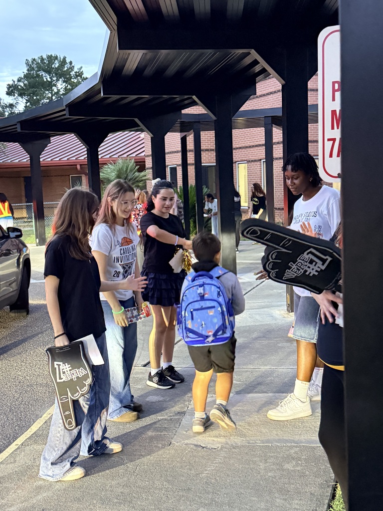 Five people in front of a shelter. One holds a sign. A boy with a backpack stands nearby.