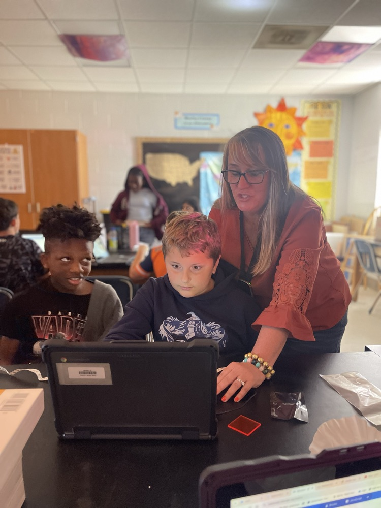 Mrs.Grooms assisting two children working on  their science lab! 