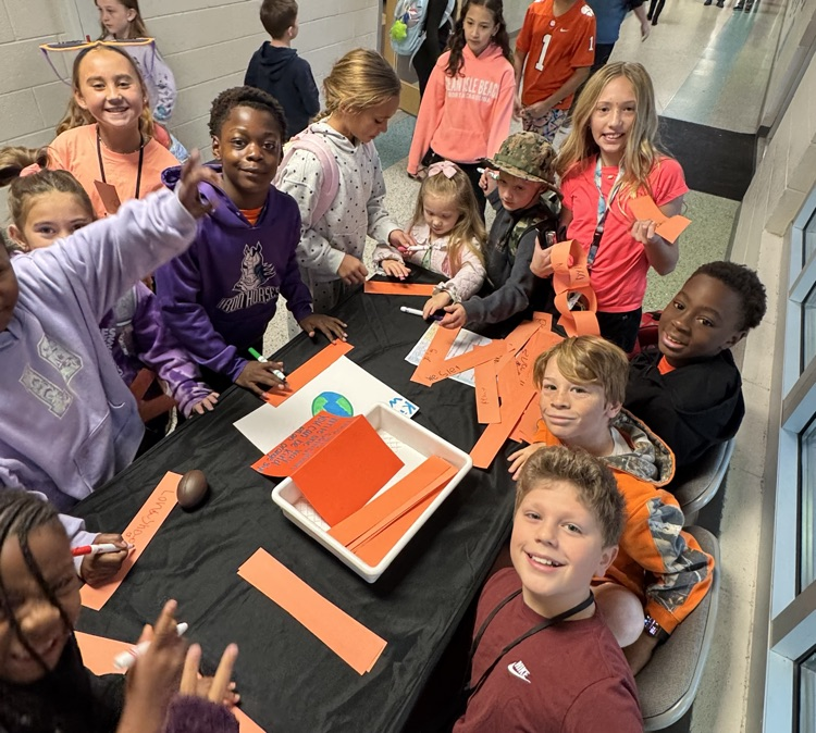 A group of students in a school corridor working on a project at a table.