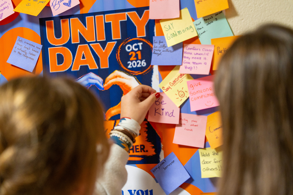 Two girls looking at a bulletin board with colorful sticky notes attached to it.