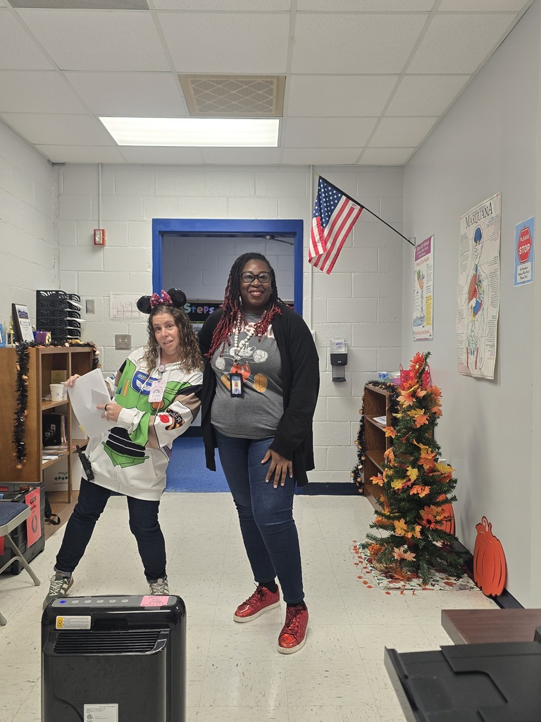 Two women standing in a hallway, one in costume, one in athletic wear. A Christmas tree behind them.