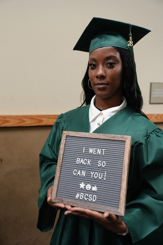 brittany with sign that reads "i went back, so can you"