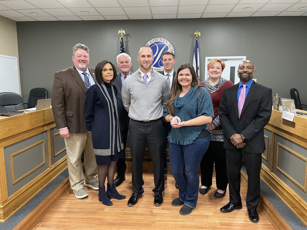 image of a caring educator award recipient standing with principal and board of education members