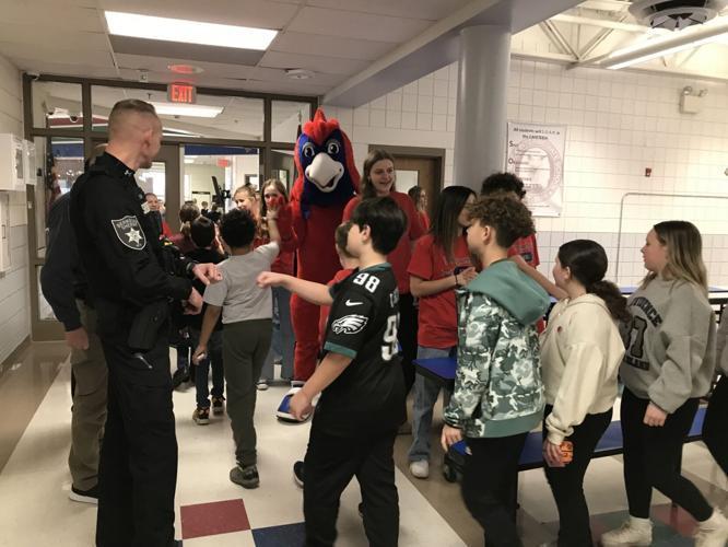 Members of Spring Mills High School Student Leadership and their mascot give high fives after the safety presentation at Potomack Intermediate School.
