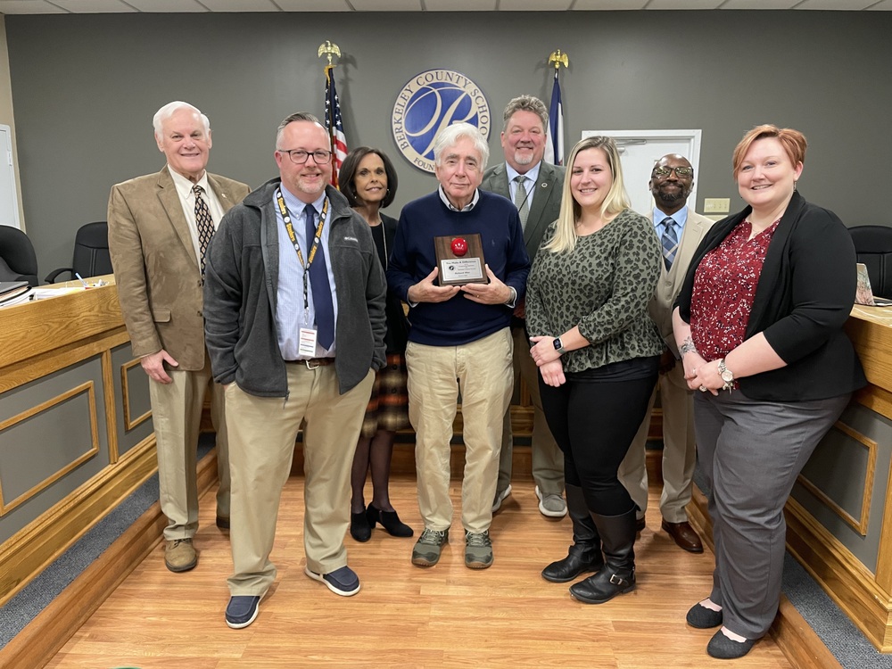 image of volunteer of the month richard mier receiving award from board members of superintendent
