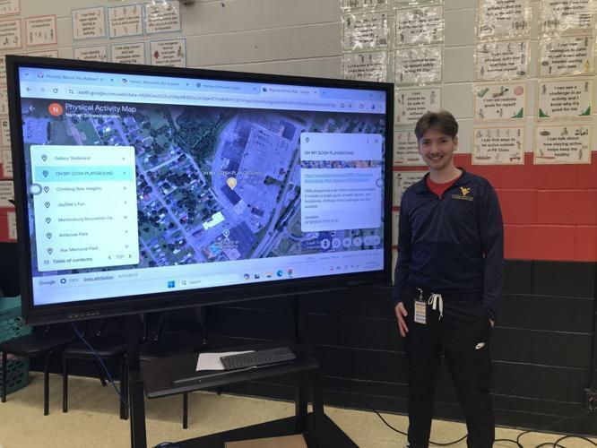 P.E. teacher Nathan Schweinebraten stands by his Physical Activity Map at Gerrardstown Elementary School's Winter Wellness event.