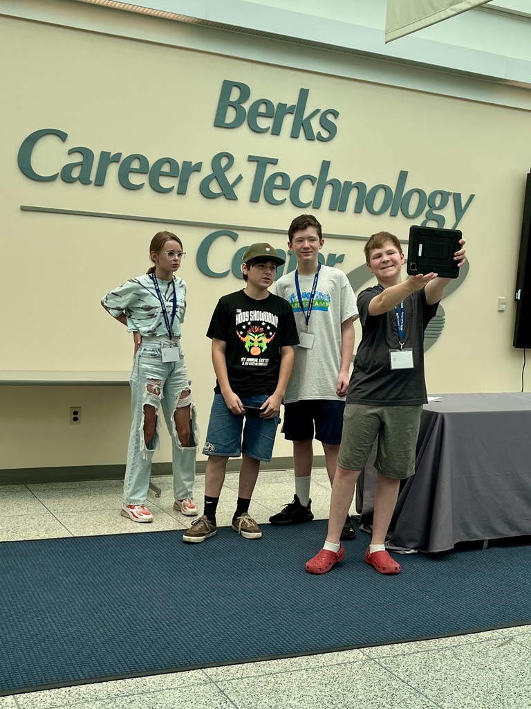 four individuals standing in front of a wall that reads "Berks Career & Technology Center." One of them is holding a tablet, likely taking a selfie or group photo.