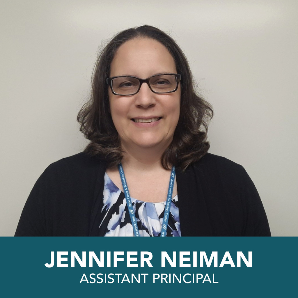 A person with a blurred face is shown wearing glasses and a lanyard. The background is plain. At the bottom of the image, text reads: "JENNIFER NEIMAN ASSISTANT PRINCIPAL."