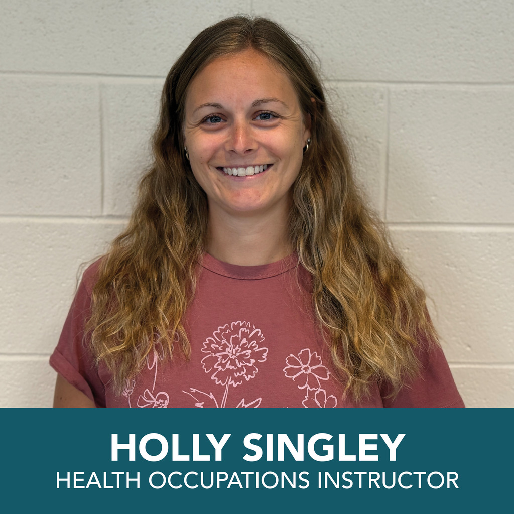 A person with long, wavy hair is shown wearing a maroon t-shirt with floral designs. At the bottom of the image, text reads: "HOLLY SINGLEY HEALTH OCCUPATIONS INSTRUCTOR."