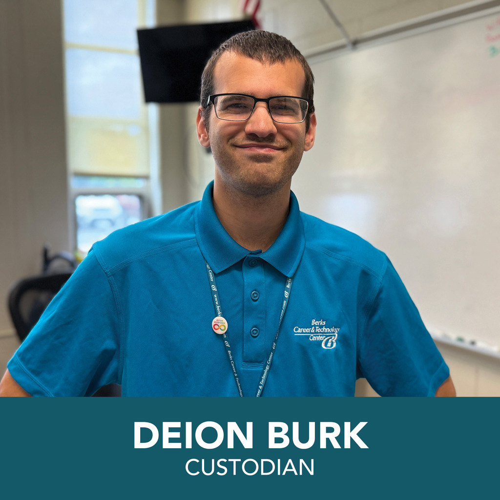 A person is shown wearing a blue polo shirt with the logo and text "Berks Career & Technology Center." They also have a lanyard with badges around their neck. The background includes a whiteboard and part of a window. At the bottom of the image, text reads: "DEION BURK CUSTODIAN."