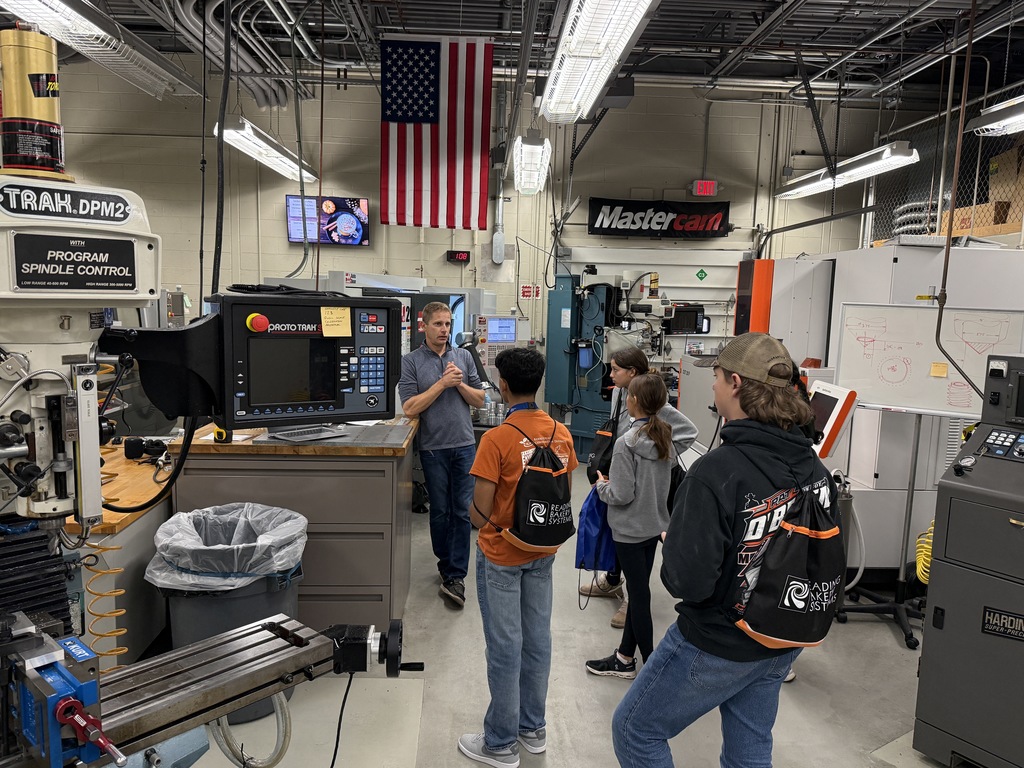 A small group of students tours BCTC’s Precision/Computerized Machining Technology lab. The instructor explains the use of CNC equipment while standing beside a ProtoTRAK control panel and milling machine.