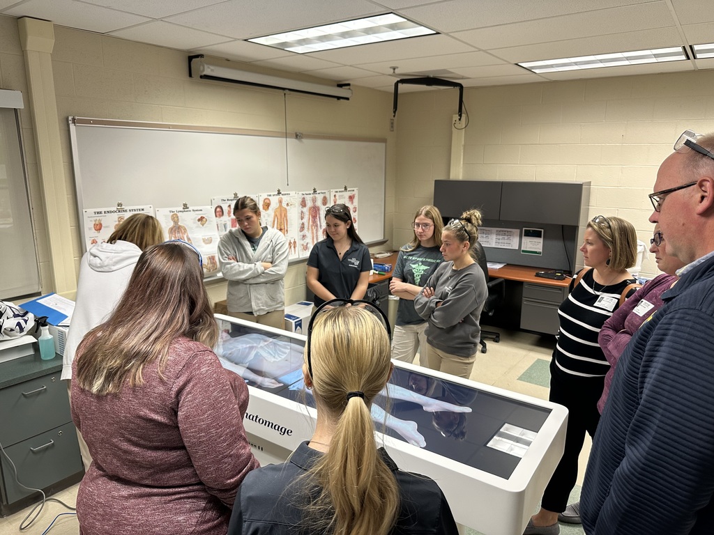 Educators observe BCTC Health Occupations students demonstrating the Anatomage Table. The digital dissection display shows a 3D human anatomy model as part of a health science presentation.