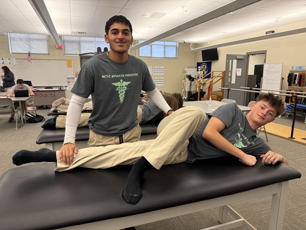 Two Sports Medicine & Rehabilitative Therapy students work together during a manual muscle test in the lab. One student stands beside the table applying resistance to his classmate’s leg while the other lies on his side for the exercise.