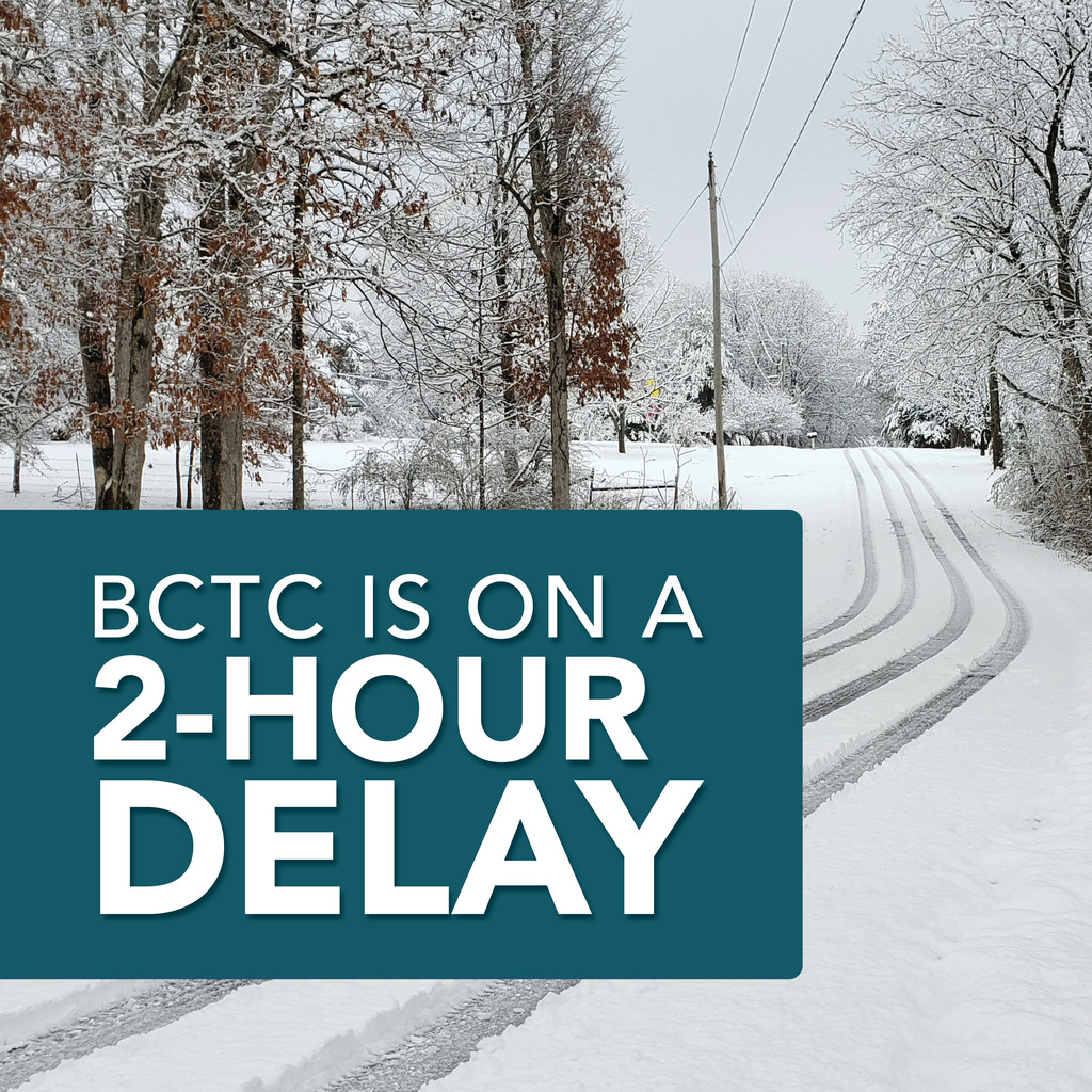 Snow-covered rural road with tire tracks leading into the distance, lined by trees coated in snow and a utility pole with wires overhead. A large teal rectangle in the foreground contains white text that reads: “BCTC is on a 2-hour delay.”
