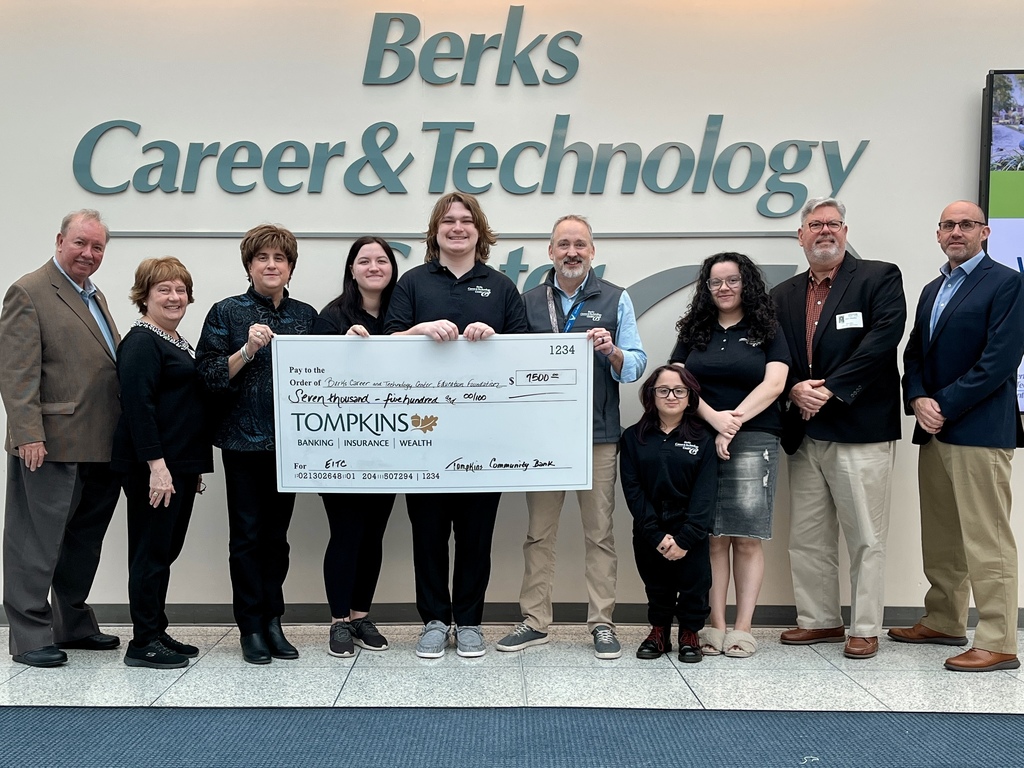 A group of adults and students stand together in front of a wall sign reading “Berks Career & Technology Center.” They are smiling while holding an oversized ceremonial check from Tompkins Community Bank made out to the BCTC Education Foundation for $7,500.