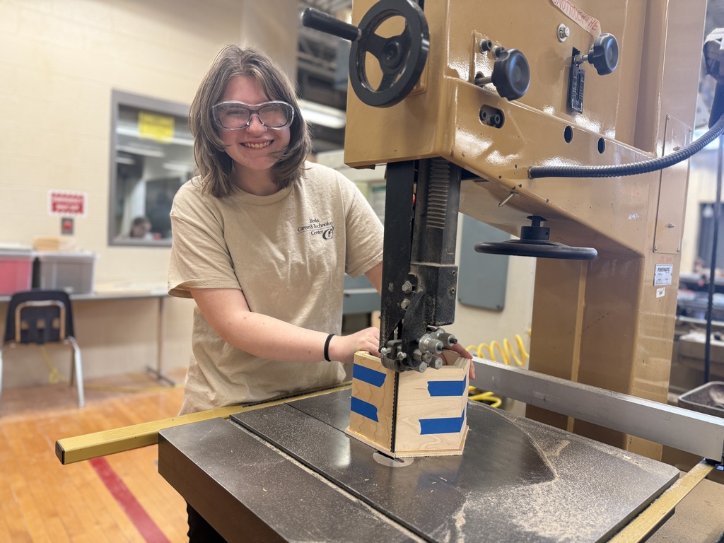 Student wearing safety glasses uses a band saw to cut an octagon-shaped wooden box in the Cabinetry & Wood Technology shop.