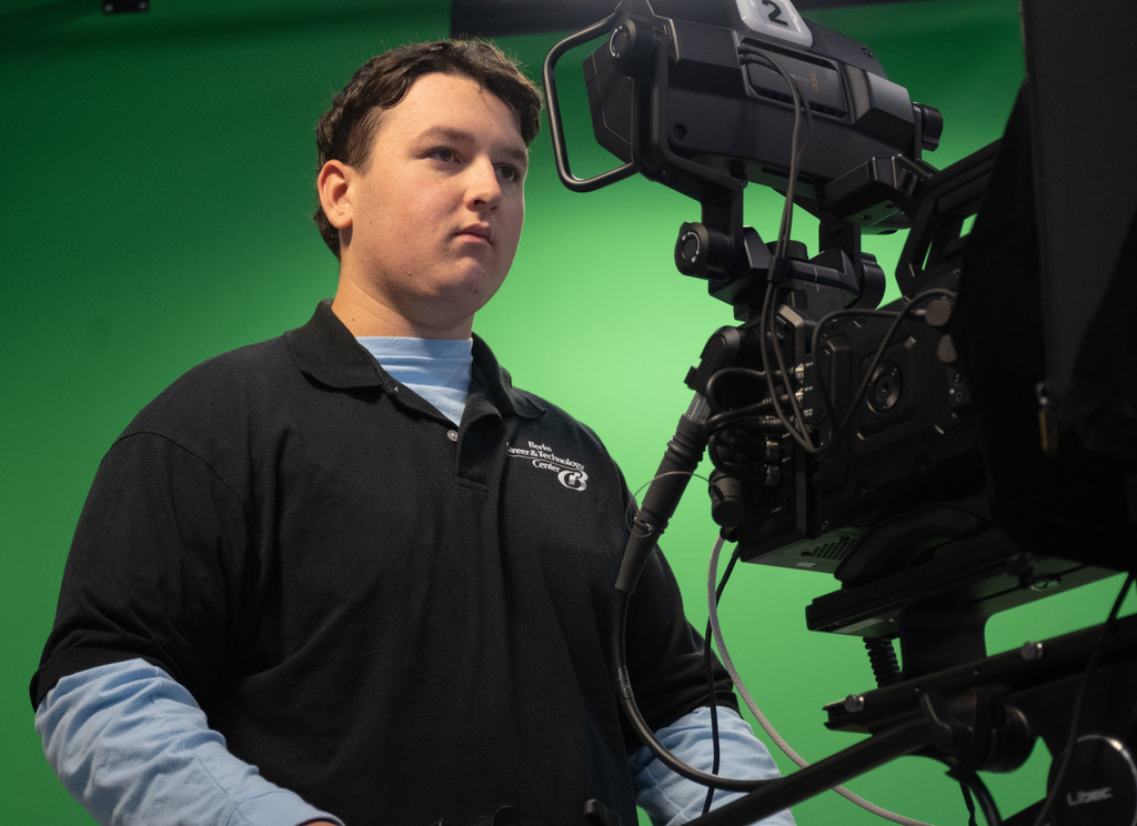 Video and Media Content Production student operates a professional video camera in front of a green screen studio backdrop.