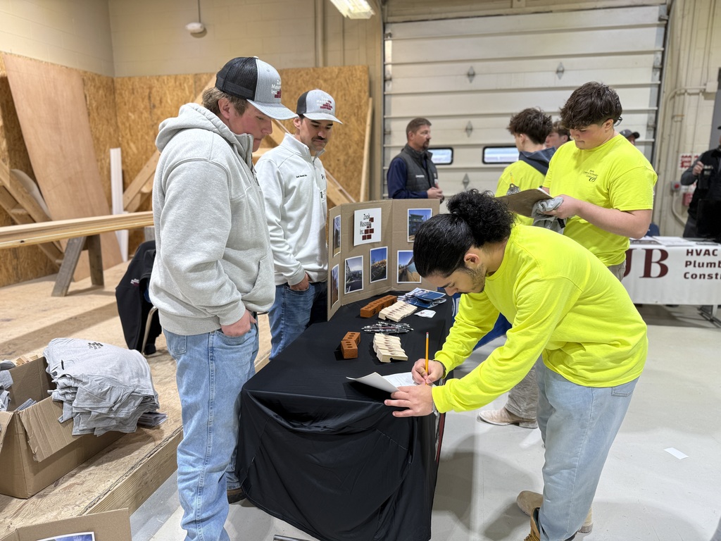 Students in a BCTC construction lab speak with industry representatives at a display table during Construction and Transportation Career Day, reviewing materials and completing sign-in paperwork.
