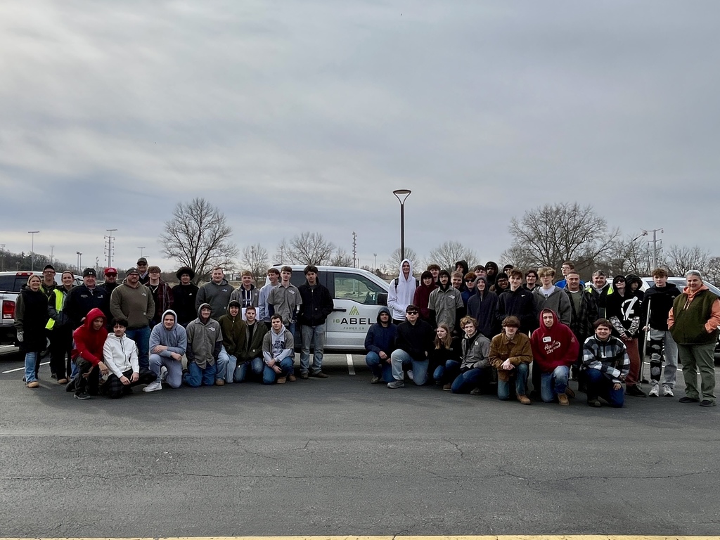 Large group of Electrical Occupations students and I.B. Abel team members gathered near a work vehicle.
