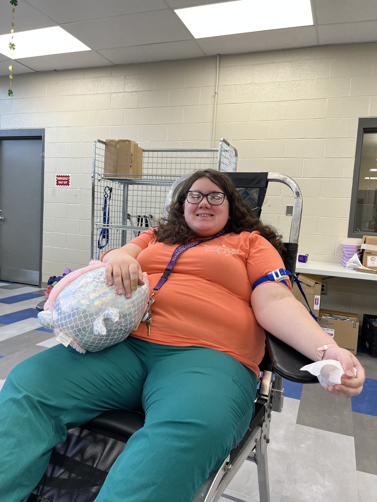 Student donor wearing an orange shirt reclines in a blood donation chair while holding a plush pillow during the Miller-Keystone blood drive at BCTC.