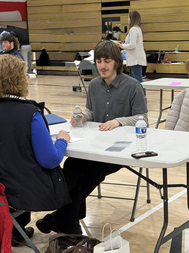 Service Occupations student speaks with an interviewer during a mock interview while others participate in interviews in the background.