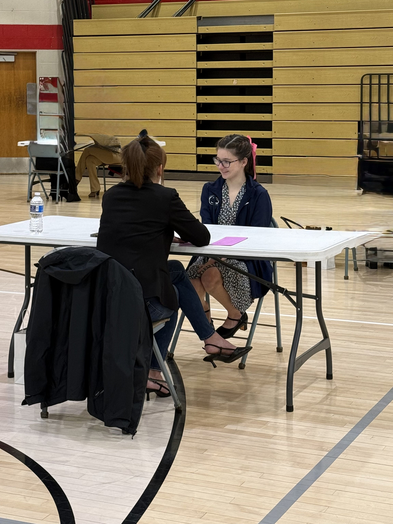 Service Occupations student participates in a mock interview with a professional during an Employability Expo event in a school gymnasium.