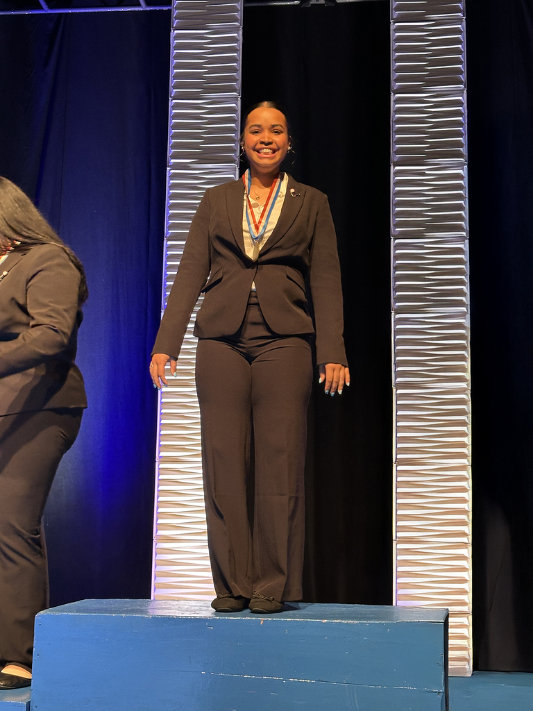 Student wearing a medal stands on a podium on stage during the Penn HOSA State Leadership Conference awards ceremony.