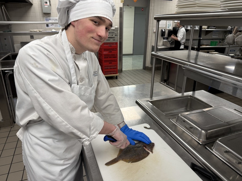Culinary Arts student fillets a flatfish on a cutting board while working in the BCTC training kitchen.
