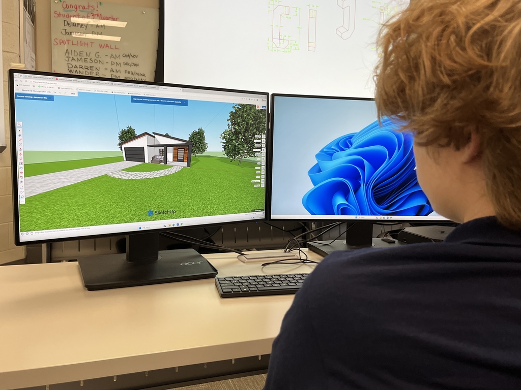Student working at dual monitors, displaying a 3D home rendering with landscaping and driveway in SketchUp.