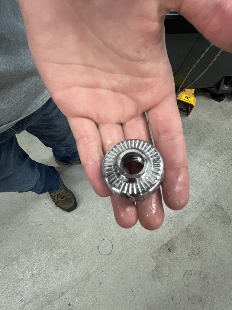 Close-up of a finished metal jam wheel resting in a student’s hand, showing detailed ridges and center opening.