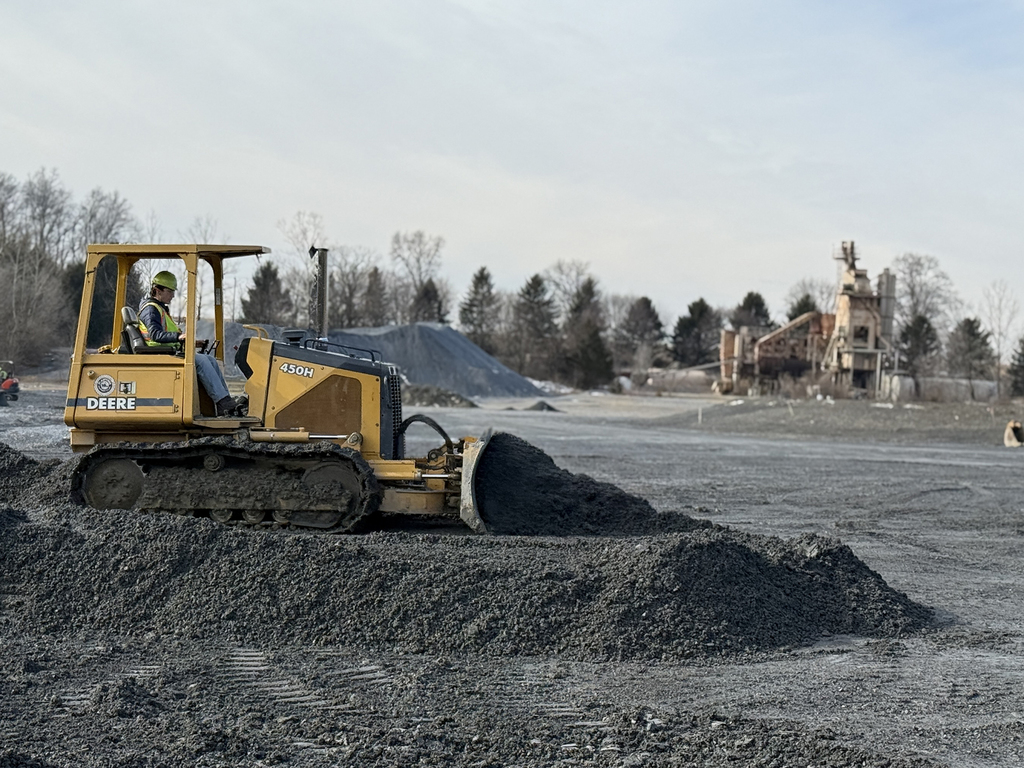 Bulldozer spreads and levels gravel across a work area in a quarry.