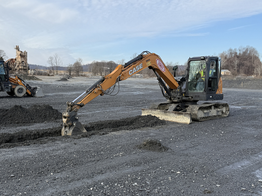 Two pieces of heavy equipment dig and move material across a quarry work area.