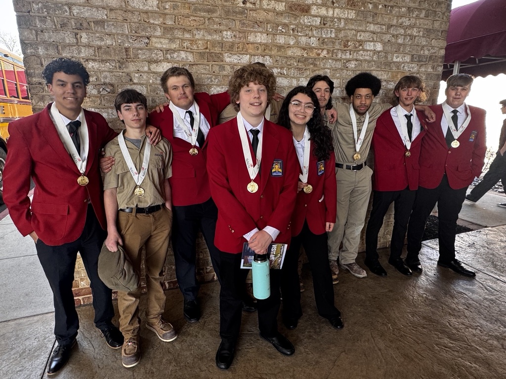 A group of BCTC students wearing red blazers and tan SkillsUSA uniforms stand together outside with their medals after the conference.