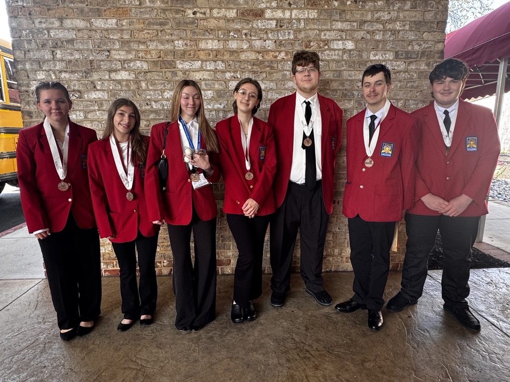 A group of BCTC students in red SkillsUSA blazers stand together outside with medals after the conference, posing in front of a brick wall.
