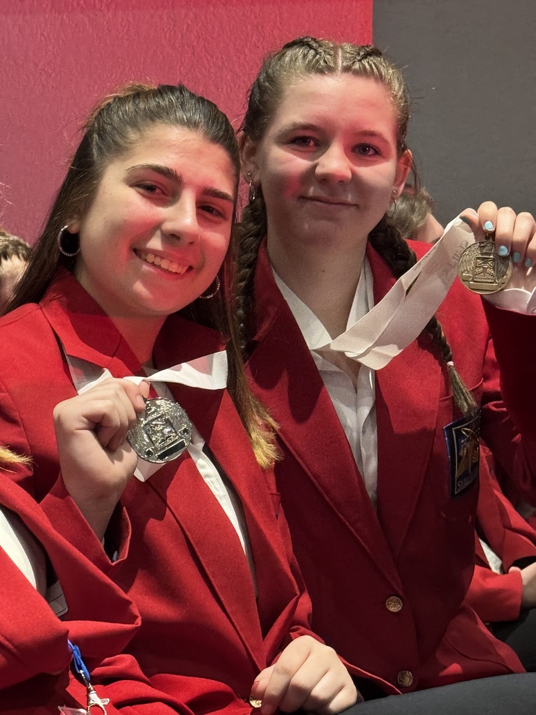 Two BCTC students in red SkillsUSA blazers smile while holding up their medals during the awards ceremony.