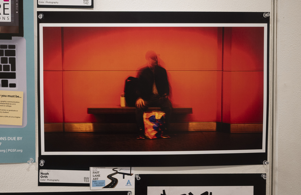 Photograph with a red-toned blurred figure sitting on a bench, creating a motion effect.