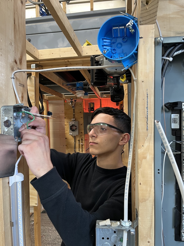 Students install metal electrical boxes and prepare them for wiring.