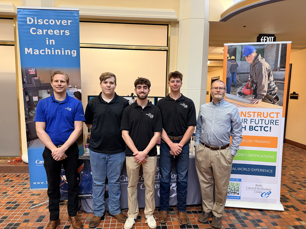 Five BCTC students and instructors from Precision/Computerized Machining Technology stand at a display with banners promoting machining careers and hands-on training.